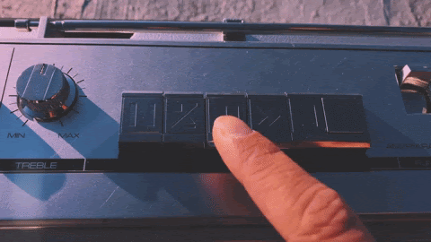 Dedo presionando el botón rebobinar de una radio antigua
